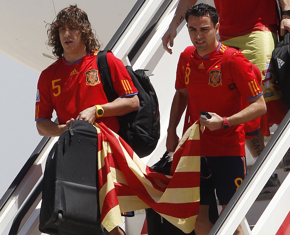 Xavi Hernández y Carles Puyol bajan las escalerillas del avión portando la bandera de Cataluña