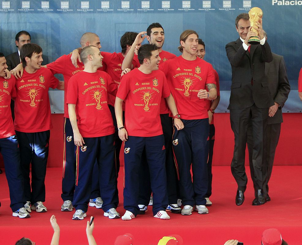 Zapatero bota con el trofeo en la mano junto a los jugadores de la Roja.