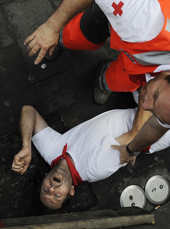 An unidentified runner is attended by medical services corner during the ninth running of the bulls of the San Fermin festival in Pamplona