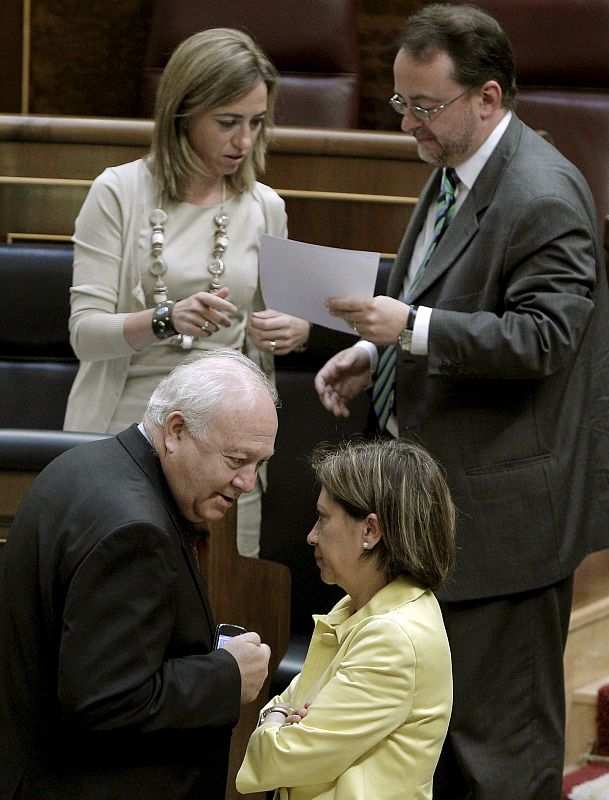 El ministro de Asuntos Exteriores, Miguel Ángel Moratinos, conversa con la ministra de Medio Ambiente y Medio Rural, Elena Espinosa, mientras la ministra de Defensa, revisa un documento al finalizar el debate.