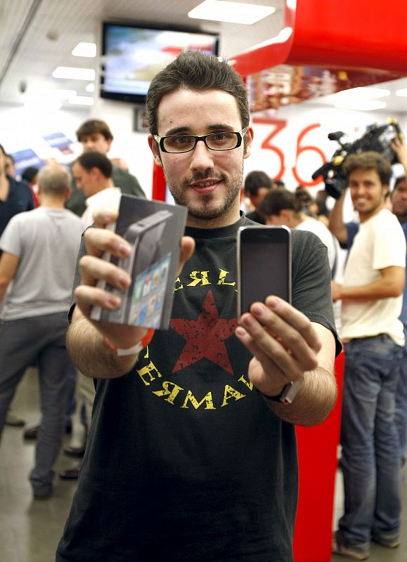 Uno de los primeros compradores del último móvil  de Apple, el iPhone 4, posa con él tras conseguirlo en una de las tiendas que han abierto esta medianoche en Madrid