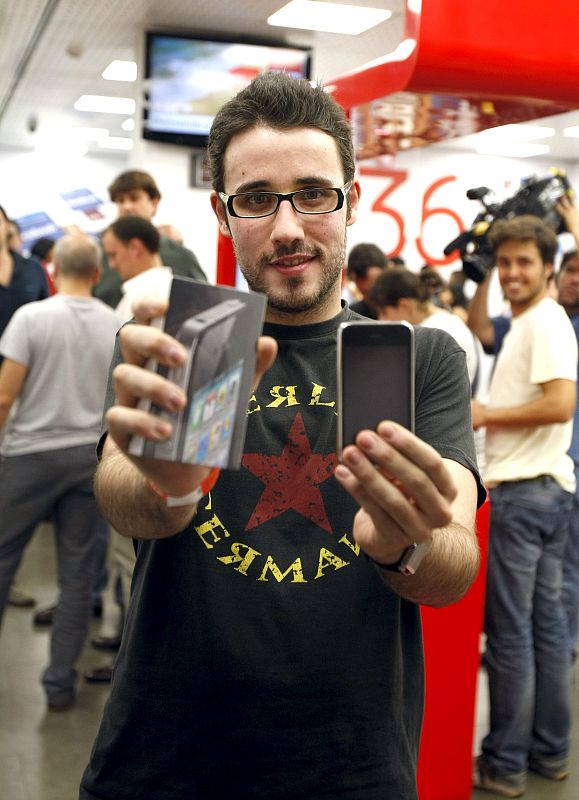 Uno de los primeros compradores del último móvil  de Apple, el iPhone 4, posa con él tras conseguirlo en una de las tiendas que han abierto esta medianoche en Madrid