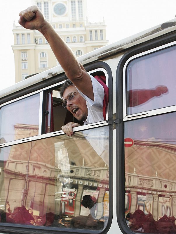 An opposition party supporter waves from a police bus after he was detained during an unauthorized protest rally in Moscow