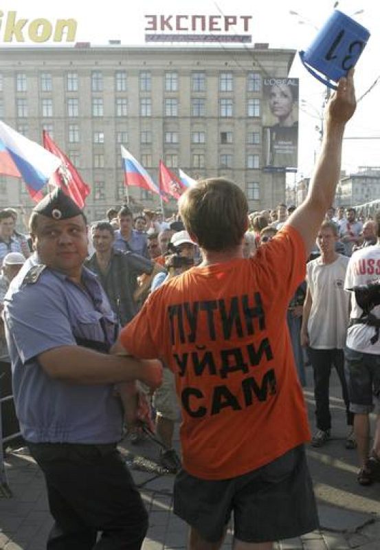 A Russian policeman detains an opposition party supporter, holding a blue bucket symbolizing blue strobe lights used by emergency services, during an unauthorized protest rally in Moscow
