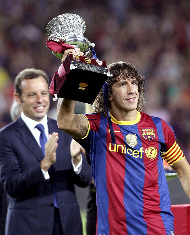 Carles Puyol levanta la copa ante los aplausos de su presidente, Sandro Rosell.