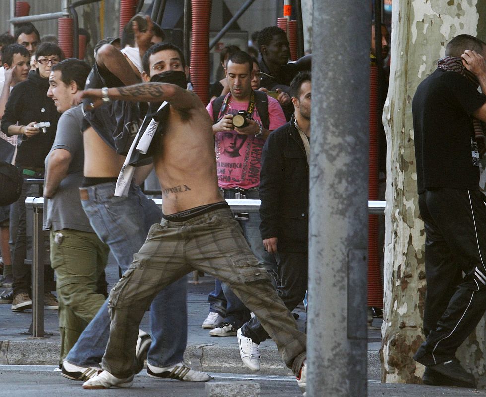 A protester throws a rock at riot police during a general strike in central Barcelona