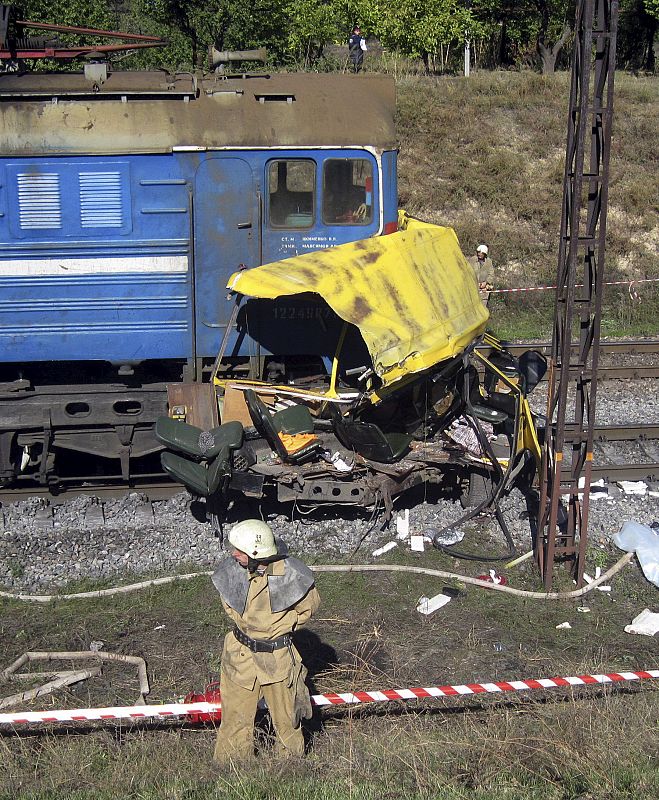 Miembros de los servicios de emergencia ucranianos inspeccionan el lugar después de que una locomotora colisionara con un autobús de pasajeros en la región de Dnipropetrovsk, al sureste de Ucrania.