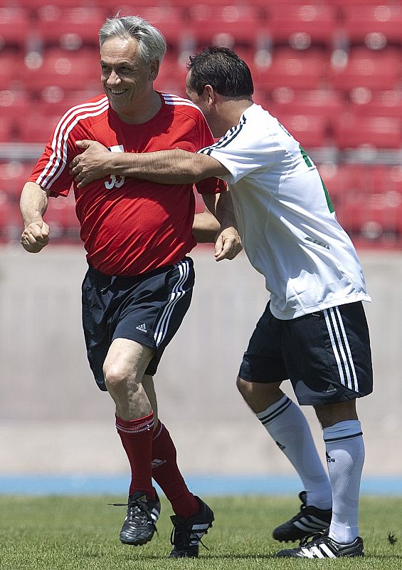 El presidente Sebastián Piñera celebra un gol, mientras es abrazado por el minero Claudio Acuña en un partido amistoso entre los 33 mineros de Atacama y funcionarios del Gobierno en el Estadio Nacional en Santiago.