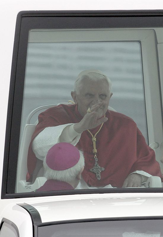 El papa Benedicto XVI saluda desde el papamóvil al abandonar el aeropuerto de Lavacolla, donde se ha reunido durante unos minutos con los Príncipes de Asturias.