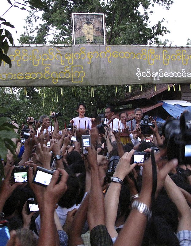 Nobel Peace Prize Laureate Aung San Suu Kyi greets supporters outside her home, which she was placed under house arrest for seven years, in Yangon