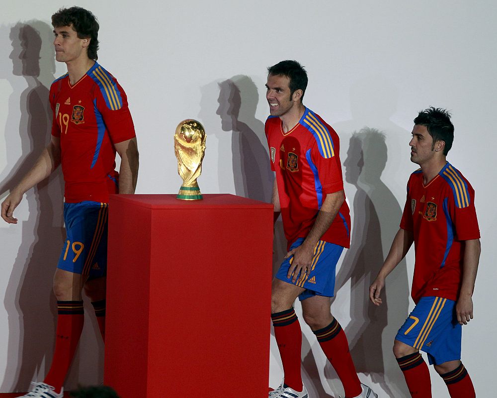 Fernando Llorente, Carlos Marchena y David Villa pasan junto a la Copa del Mundo conquistada en el Mundial Sudáfrica 2010 con la nueva equipación de La Roja durante el homenaje que recibieron, que contó con la asistencia de los futbolistas que ha