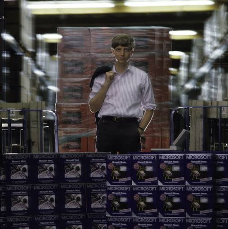 1986:  Bill Gates posa junto a cientos de cajas de productos de Microsoft en Redmond, Washington. 