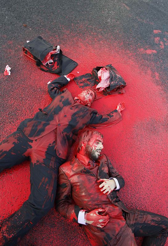 People lie in red paint on a road during protests against the NATO summit in Lisbon