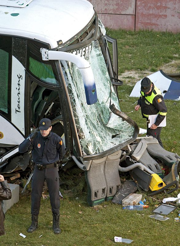 Un policía inspecciona el autobús que cayó por un terraplén al intentar evitar la colisión con otro vehículo.