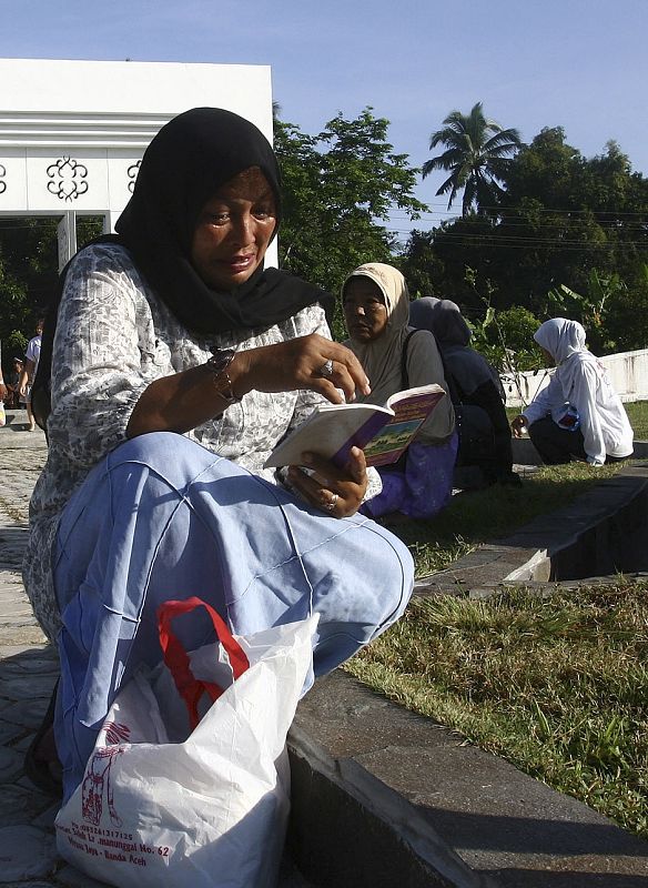 An Acehnese woman prays while crying for family members who died in the 2004 tsunami, at the Lambaro mass grave near Banda Aceh