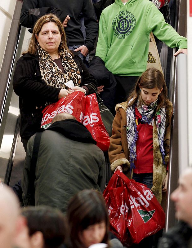 Un grupo de persona descienden con sus compras por una escalera mecánica de una superficie comercial de Pamplona,