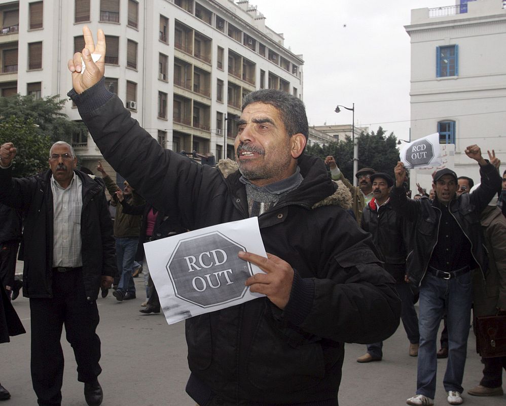 Un manifestante porta una cartel donde se lee 'Fuera RCD' durante una protesta contra la presencia de miembros de la Reagrupación Constitucional Democrática (RCD) en el nuevo Gobierno de transición del país