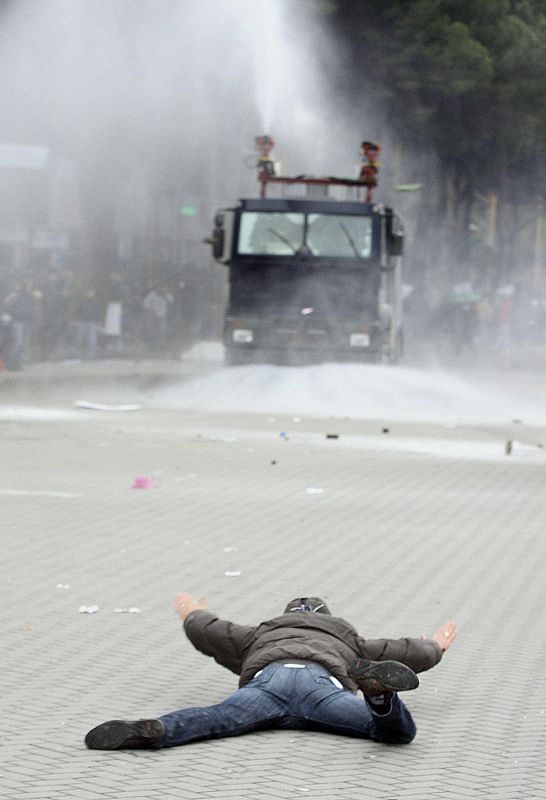 Un partidario del opositor Partido Socialista aparece tirado en la principal avenida de la capital albanesa frente a un cañón de agua de la policí