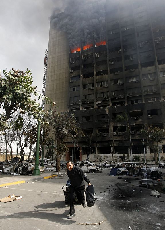 A looter runs away from the burning building of the ruling National Democratic party in Cairo