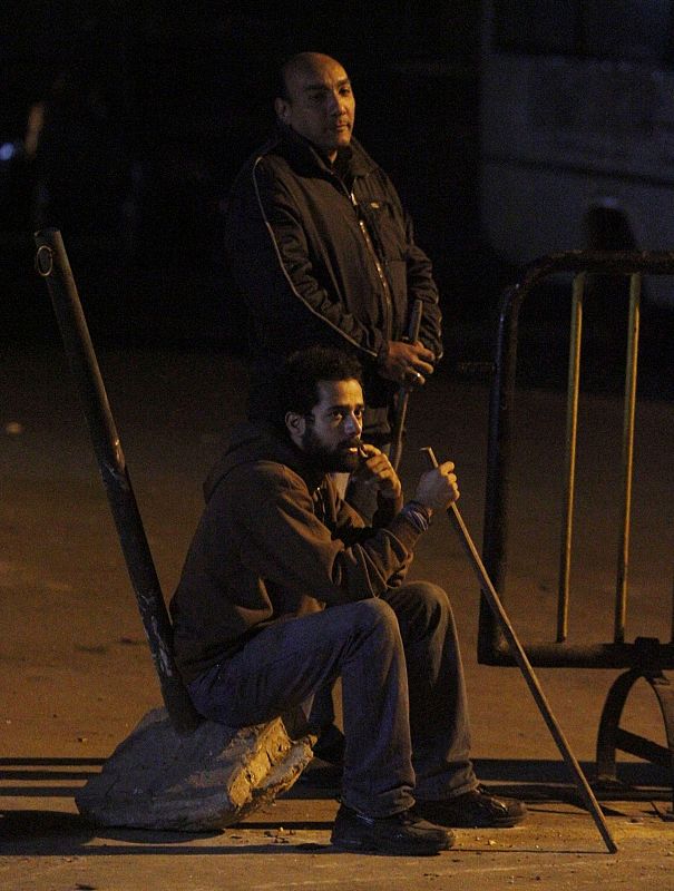 Local residents sit as they secure property and families from looters, in Cairo