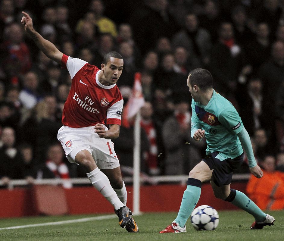 Theo Walcott lucha por el balón con Andrés Iniesta.