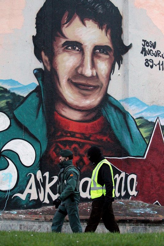 Dos guardias civiles pasan ante un mural con la imagen del histórico dirigente de Batasuna Josu Muguruza