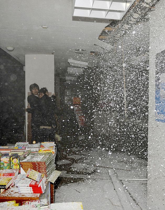 People take shelter as a ceiling collapses in a bookstore during an earthquake in Sendai