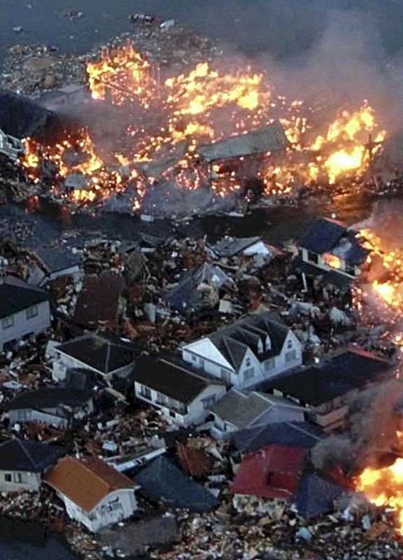 Houses swept out to sea burn following a tsunami and earthquake in Natori