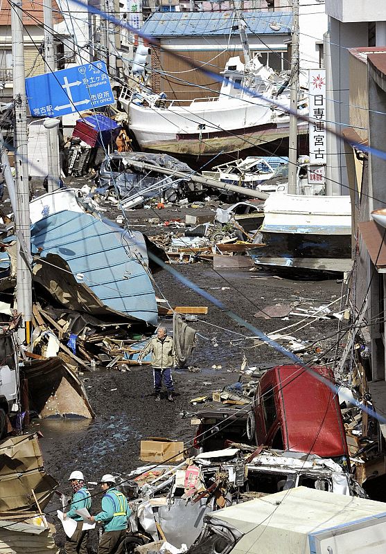 A man walks among debris and strewn boats after a tsunami in Miyako City, Iwate Prefecture