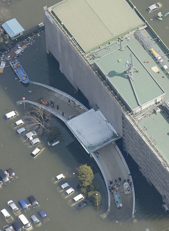 People evacuate by boats from a building in Ishimaki City
