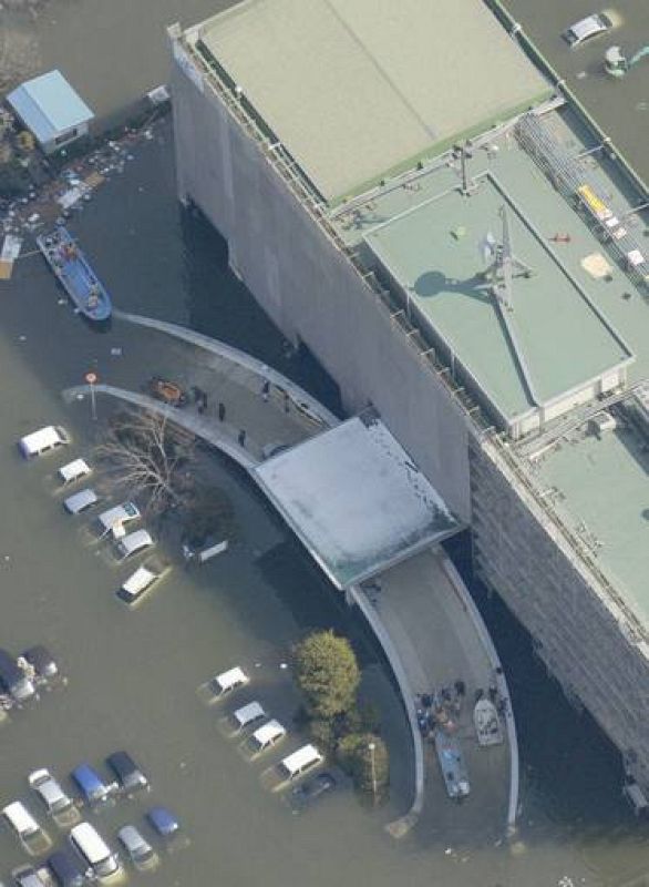 People evacuate by boats from a building in Ishimaki City