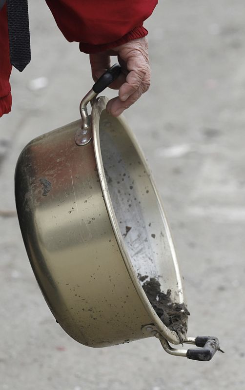 A woman carries a pot which she found at her destroyed house in Kamaishi