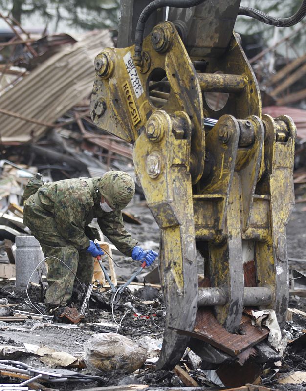 A Japan Self Defense Force officer works to remove debris and to rebuild a village destroyed in Kamaishi