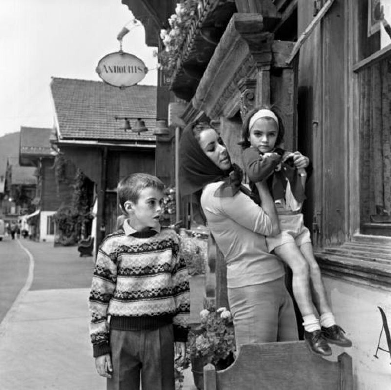 Imagen de archivo tomada el 20 de julio de 1962 que muestra a la actriz Elizabeth Taylor junto a sus dos hijos en la puerta de un anticuario en Gstaad, Suiza. 