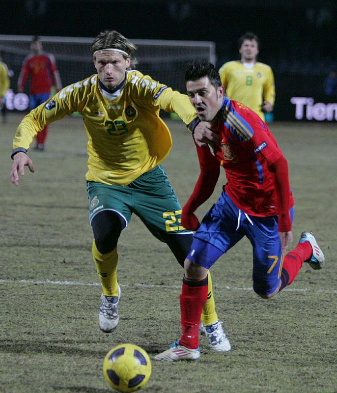 El jugador de Lituania Marius Stankevicius lucha por el balón con David Villa, de España.