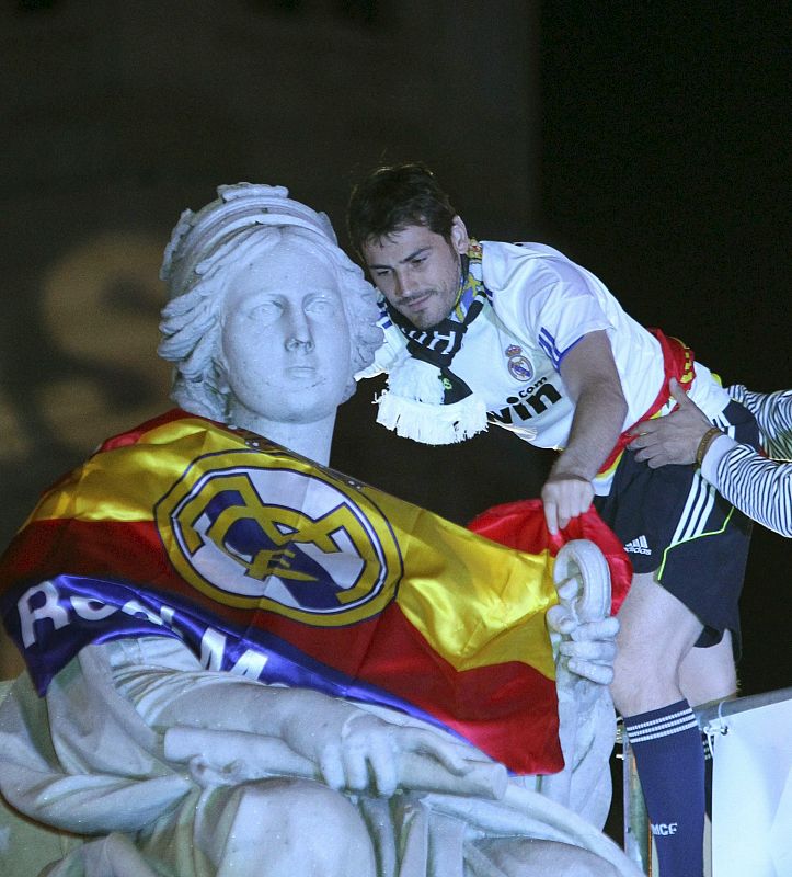 El guardameta del Real Madrid, Iker Casillas, coloca una bandera en la estatua de La Cibeles, celebrando la victoria del equipo blanco.