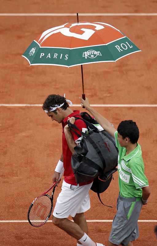 El tenista suizo Roger Federer sale de la pista central a causa de la interrupción por la lluvia de la final del torneo de Roland Garros que disputa contra el español Rafael Nadal en París.