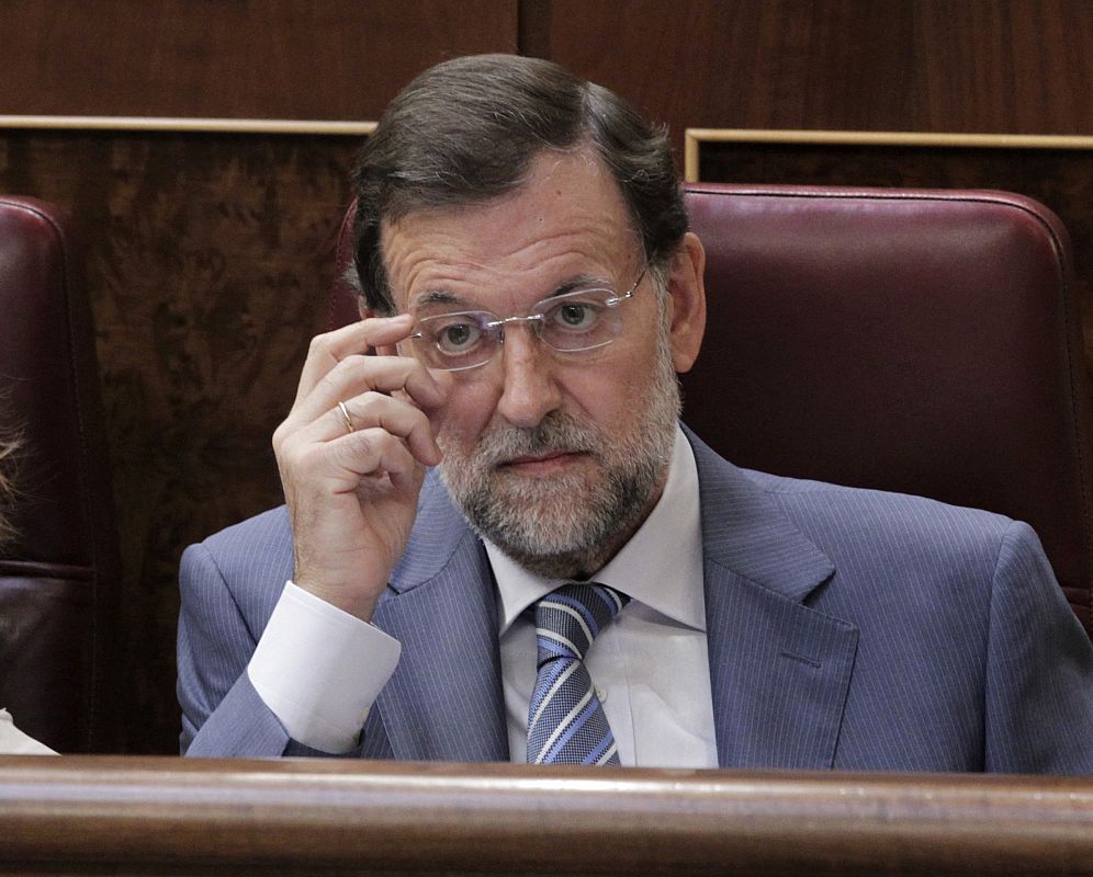 El líder del PP, Mariano Rajoy, escucha la intervención del presidente del Gobierno