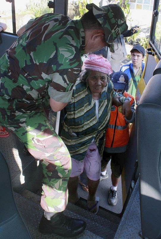 Un soldado ayuda en la evacuación de una anciana por la erupción del volcán Lokon