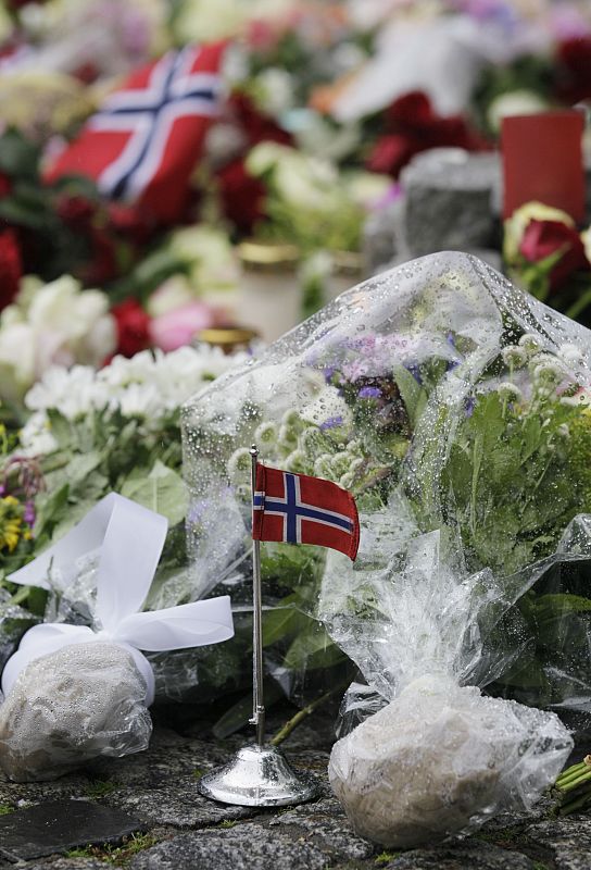 A Norwegian flag stands among flowers placed on the market square outside the Oslo cathedral to mourn the victims of a bomb blast and a rampage