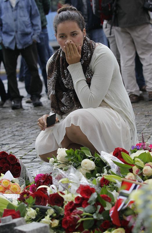 A woman mourns in front of a flowers that were placed on the market square outside the Oslo cathedral to commemorate the victims of a bomb blast and a rampage