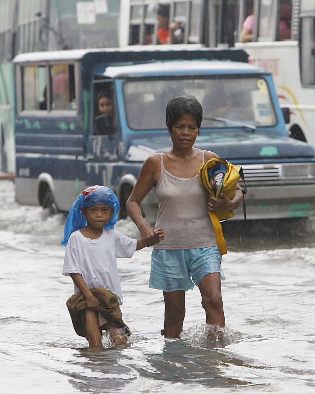 Una madre y su hijo caminan por las calles inundadas de Malabón, en el norte de Malnila