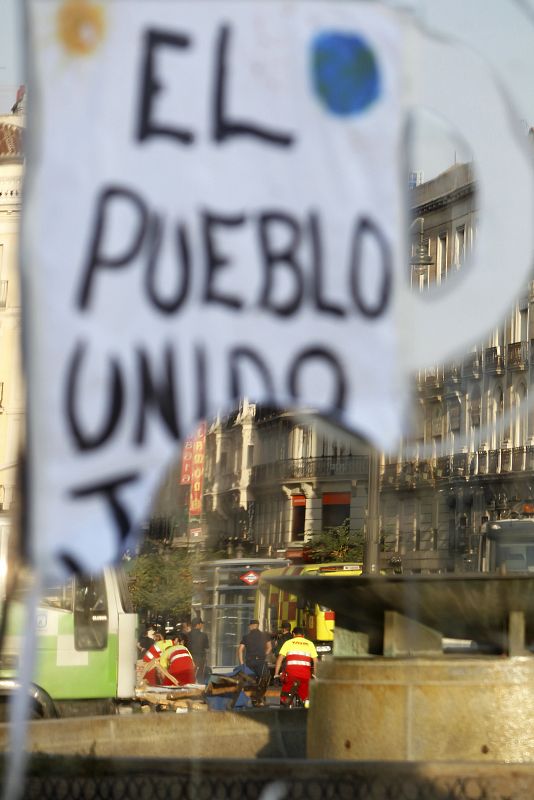 Los operarios de limpieza retiran los residuos del campamento de los indignados