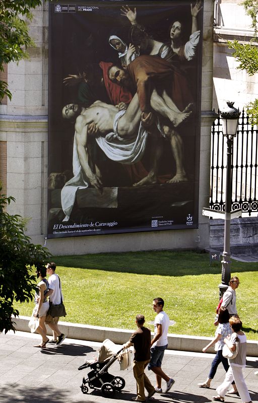 Un grupo de personas pasa por delante del Museo del Prado, donde se puede contemplar, cecido por los Museos Vaticanos, el cuadro de "El descendimiento" de Caravaggio