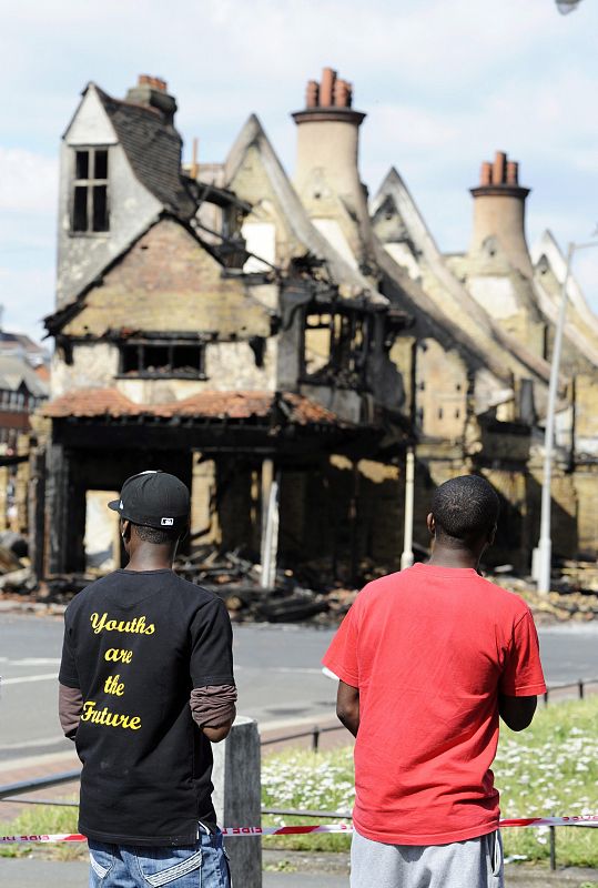 Dos hombres observan los restos de una tienda de muebles incendiada en Croydon, Londres.