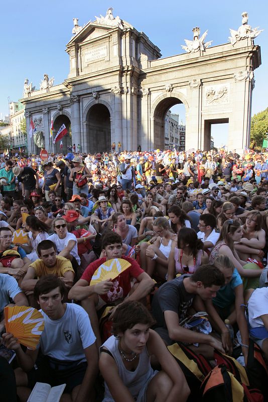 Cientos de peregrinos llegados de diferentes partes del mundo escuchan desde la Puerta de Alcalá la misa de inauguración de la Jornada Mundial de la Juventud