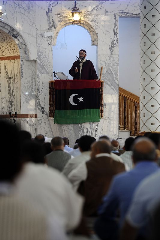 Musulmanes libios escuchan el sermon desde el púlpito engalanado con la nueva bandera