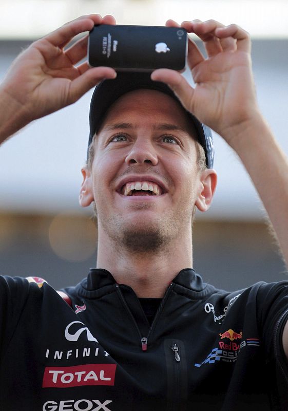 El piloto alemán de Fórmula Uno Sebastian Vettel, de Red Bull, utiliza su teléfono para fotografiar a los aficionados que le siguen en la competición.