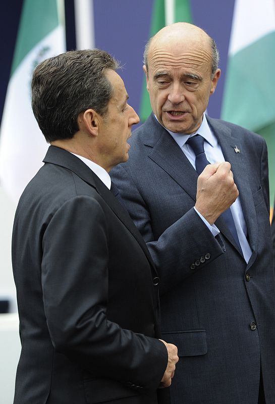 El presidente francés, Nicolas Sarkozy, habla con su ministro de Exteriores, Alain Juppe, mientras esperan la llegada de Barack Obama.