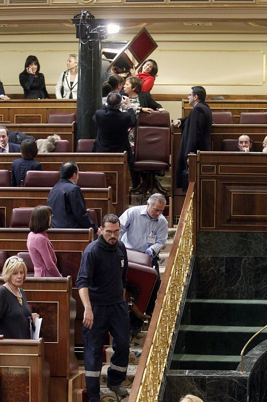 Varios operarios del Congreso colocan butacas en el hemiciclo para que los senadores asistan al debate de investidura.